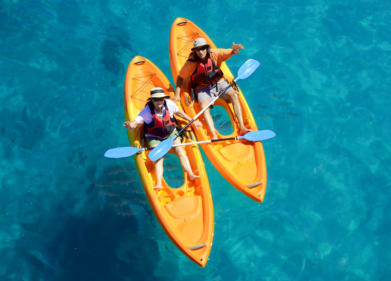 Two orange Easy Kayaks glass-bottom kayaks floating over clear blue water