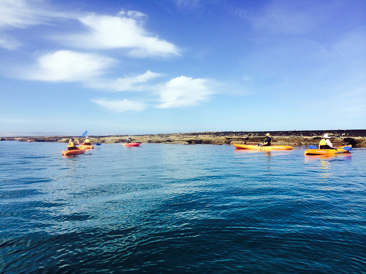 Kayakers crossing calm water toward the reef